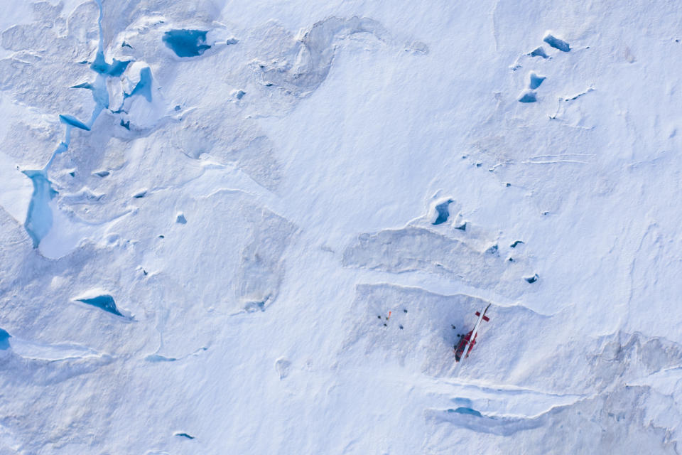 In this Aug. 16, 2019, photo, a helicopter carrying New York University air and ocean scientist David Holland and his team sits on the ice as they install a radar and GPS at the Helheim glacier, in Greenland. Scientists are hard at work there, trying to understand the alarmingly rapid melting of the ice. (AP Photo/Felipe Dana)