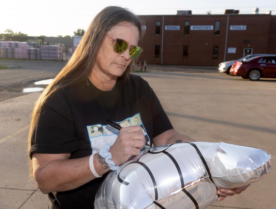 Robin Broad-Showalter, widow of Michael Broad, writes a personal message to him before she  releases a balloon to mark the 20th anniversary of his unsolved homicide.