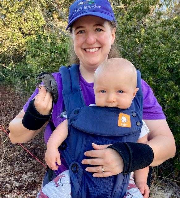 Heather Pitman holds a recently banded gray catbird while holding son, Leo.