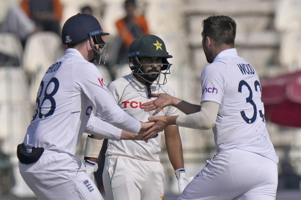 England's Mark Wood, right, celebrates with teammate after the dismissal of Pakistan's Saud Shakeel, center, during the fourth day of the second test cricket match between Pakistan and England, in Multan, Pakistan, Monday, Dec. 12, 2022. (AP Photo/Anjum Naveed)