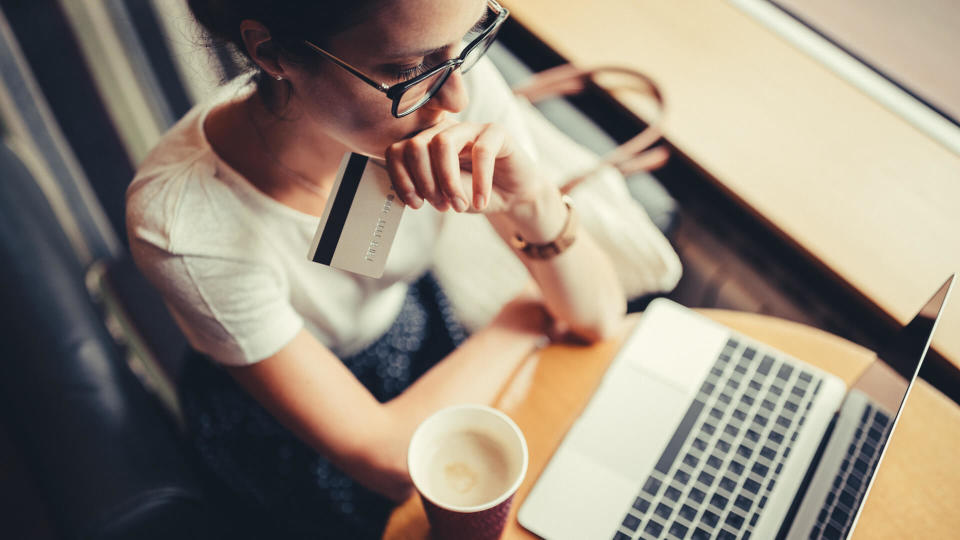 Woman in a cafe having problems with the credit card, fees, America, money, payment, avoid fees, bills, debt