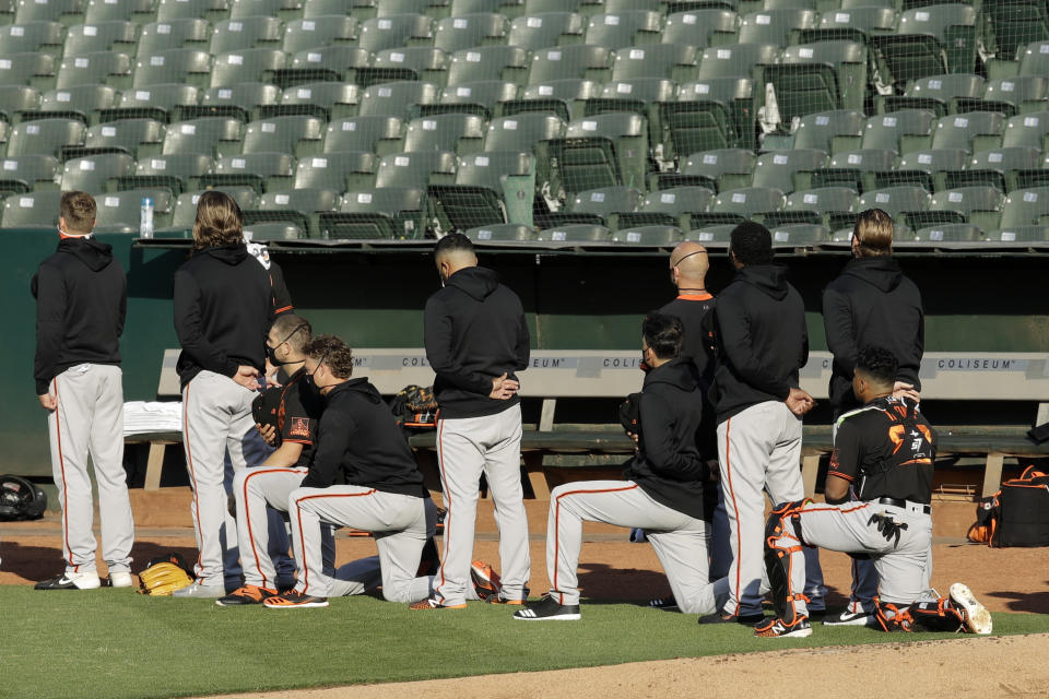 Some San Francisco Giants kneel during the national anthem prior to an exhibition baseball game against the Oakland Athletics on Monday, July 20, 2020, in Oakland, Calif. (AP Photo/Ben Margot)