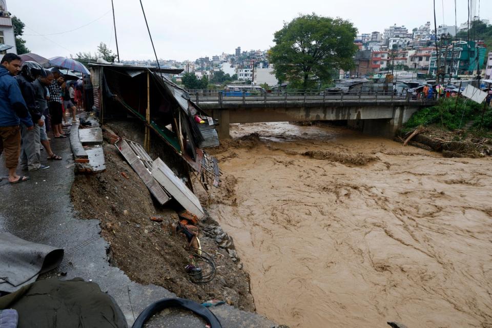 People gather at the edge of the Bagmati River in spate after heavy rains in Kathmandu, Nepal, Saturday, 28 Sept 2024 (Copyright 2024 The Associated Press. All rights reserved.)