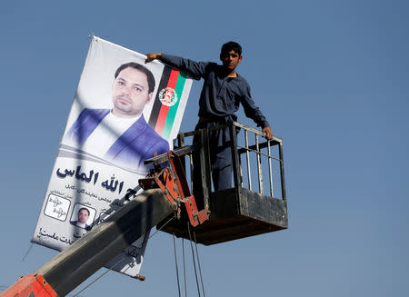 An Afghan man prepares a poster of a parliamentary election candidate ahead of the elections in Kabul, Afghanistan October 18, 2018. REUTERS/Omar Sobhani