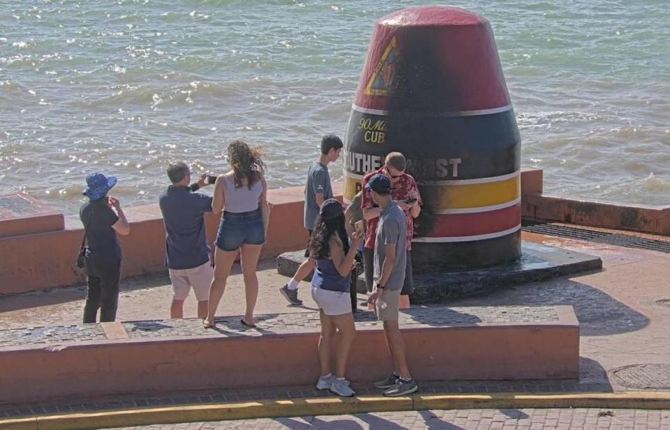 People gather near the Southernmost Point buoy in Key West for photos on Jan. 1, 2022, hours after it was left charred by a fire set by vandals, police said.