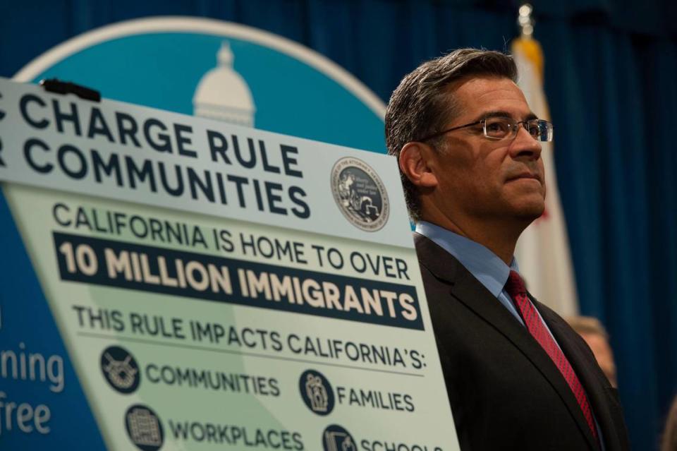 Attorney General Xavier Becerra stands near the podium during a press conference Friday to announce California will file suit against the Trump administration’s ‘public charge’ rule to deny immigrants green cards if they are likely to rely on public benefits.