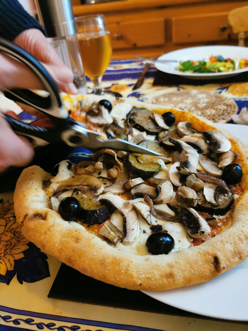 Slicing a mushroom pizza with kitchen shears.