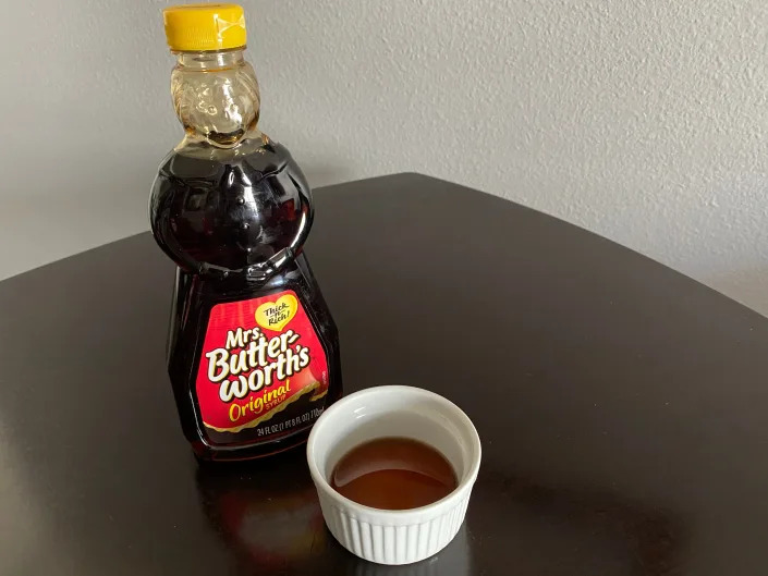 bottle of mrs. butterworths syrup next to a ramekin filled with the syrup