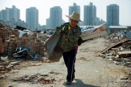 Migrant worker Wang Jun carries scrap material she collected from debris of demolished buildings at the outskirts of Beijing, China October 1, 2017. Picture taken October 1, 2017. REUTERS/Thomas Peter