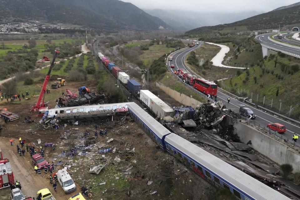 A crane, firefighters and rescuers operate after a collision in Tempe near Larissa city, Greece, Wednesday, March 1, 2023. A train carrying hundreds of passengers has collided with an oncoming freight train in northern Greece, killing and injuring dozens of passengers. (AP Photo/Vaggelis Kousioras)