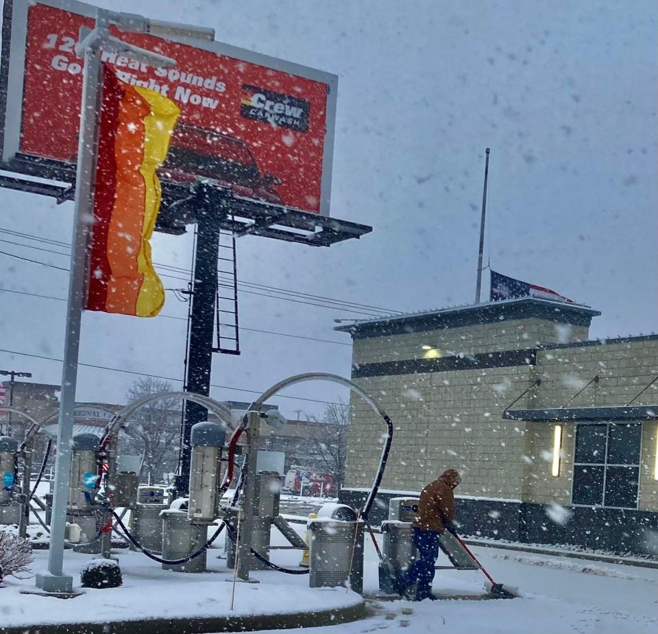 A man shovels snow at Crew Carwash along McGalliard Road at reserve Street during an ongoing snowstorm Wednesday morning.