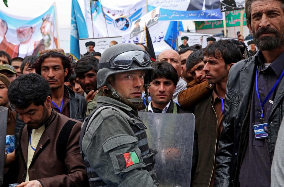 An Afghan policeman stands guard as supporters of Afghan presidential candidate Ashraf Ghani Ahmadzai listen to his speech during a campaign rally in Kabul, Afghanistan, Tuesday, April 1, 2014. Eight Afghan presidential candidates are campaigning for the third presidential election. Elections will take place on April 5, 2014. (AP Photo/Massoud Hossaini)