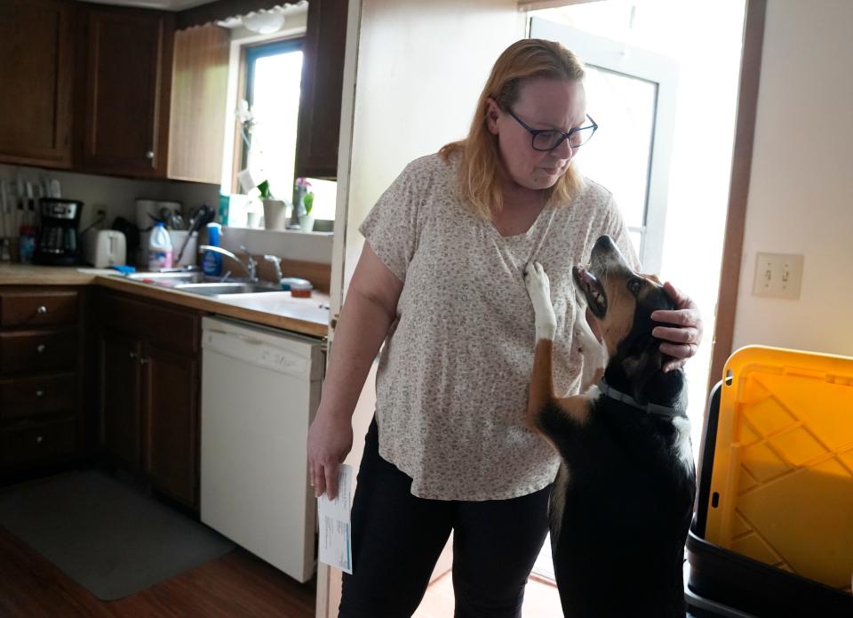 May 1, 2024; Columbus, Ohio, USA; 
Sheryl Brown pets her dog Stella while holding a water bill that was much higher than what she is used to. Peak Property Group purchased the units on Griggsview Court and changed the way billing is done for residents, many of of whom have seen substantial increases.