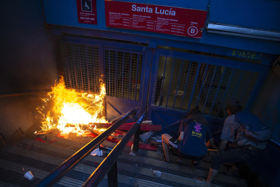 Protesters push a bicycle in front of a gate of the Santa Lucia subway station during a protest against the rising cost of subway and bus fares, in Santiago, Friday, Oct. 18, 2019. (AP Photo/Esteban Felix)