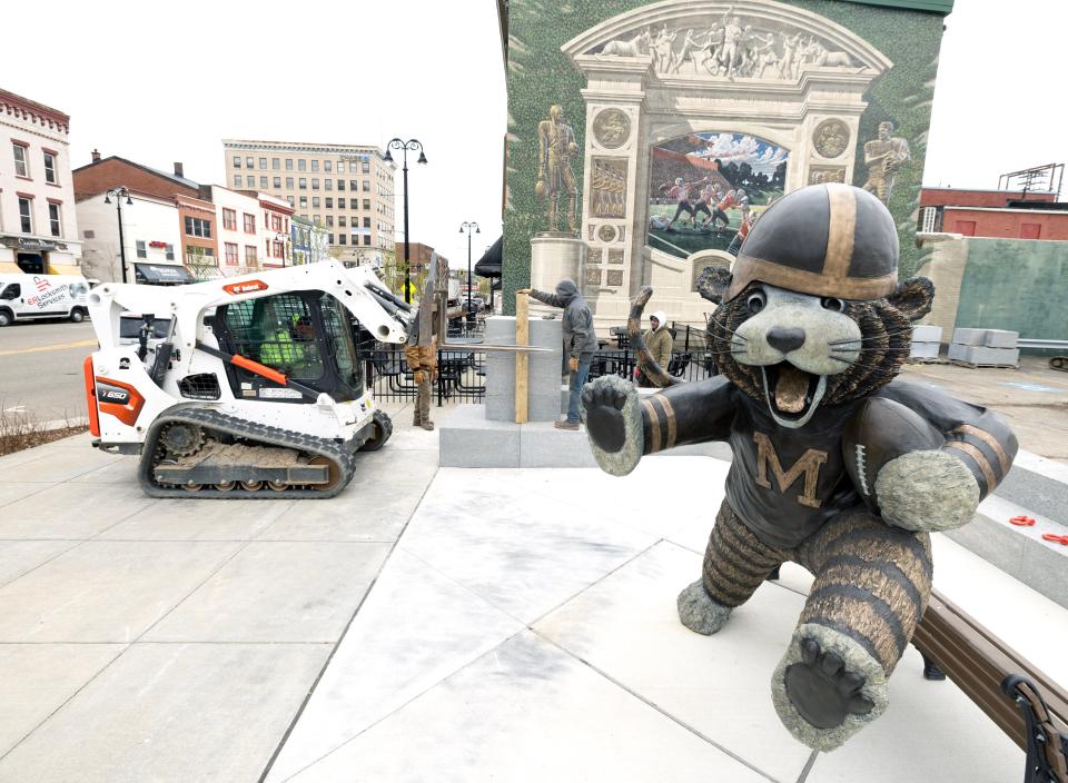 Workers from Orange Cone Concrete, a division of Massillon Washed Gravel, install a granite wall behind the Obie the Tiger statue in downtown Massillon. The wall, which features a bench, is the last piece of the project. The 8-foot bronze statue was erected at Lincoln Way E and First Street NE in 2022.