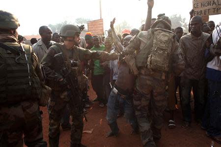 French military personnel try to control supporters who are asking them to disarm fighting gangs, near the airport in Bangui December 23, 2013. REUTERS/Andreea Campeanu