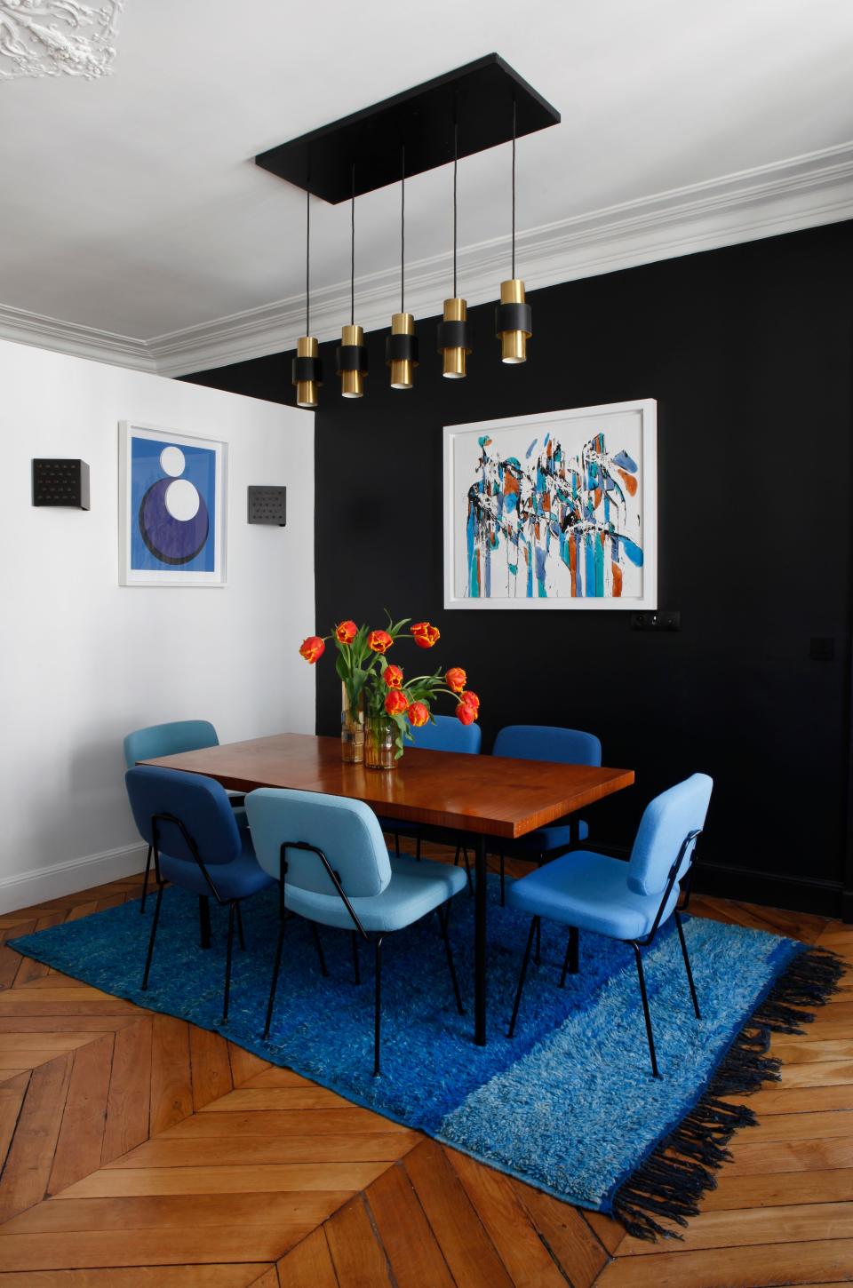 The dining room table is by Gérard Guermonprez and the chairs are Pierre Paulin. The Moroccan carpet is vintage from the 1980s. The wall lights are RAAK and the hanging fixture is “Tunika” by Jo Hammerborg for Fog & Morup.  The art is by Geneviève Claisse and the painting is by Danhoo.