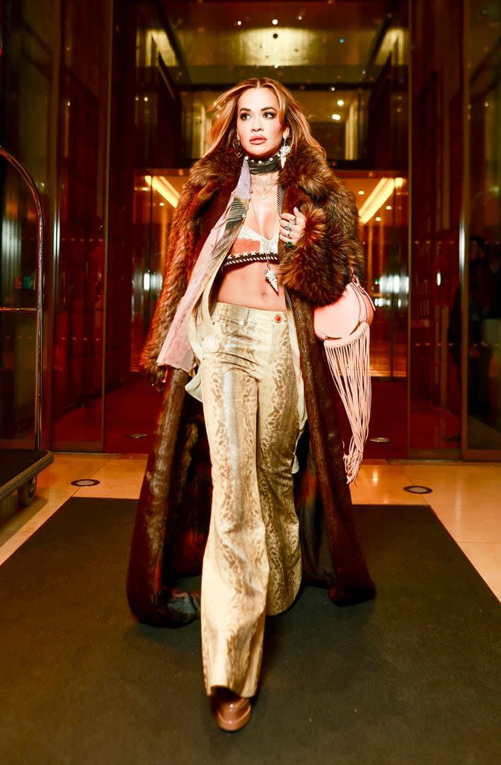 Rita Ora deslumbró con su figura. La cantante brilló en París con un conjunto del diseñador italiano Roberto Cavalli que incluyó un abrigo marrón combinado con pantalones dorados y accesorios como un pañuelo, múltiples collares y un bolso de flecos en color rosa