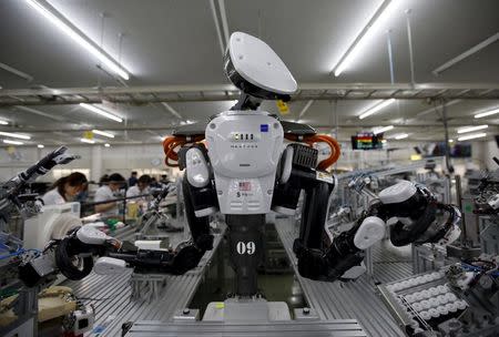 A humanoid robot works side by side with employees in the assembly line at a factory of Glory Ltd., a manufacturer of automatic change dispensers, in Kazo, north of Tokyo, Japan, in this July 1, 2015 file photo. REUTERS/Issei Kato/Files