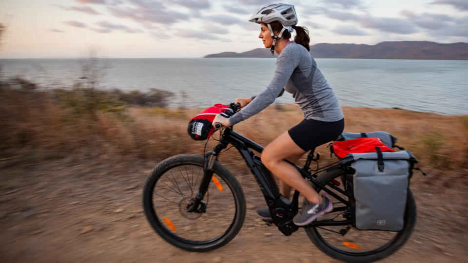 Woman bikepacking with panniers and handlebar bag on e-bike