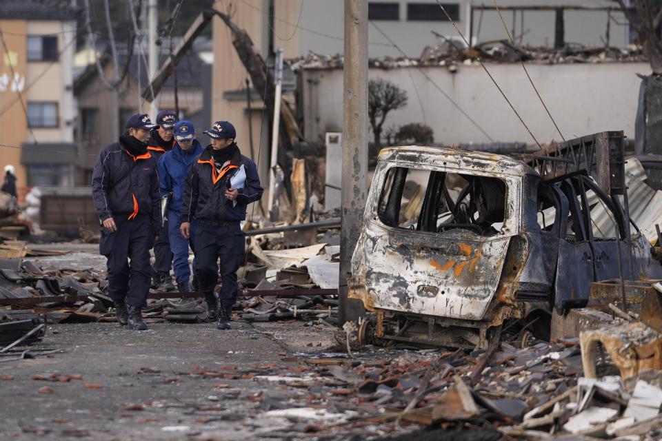 Firefighters walk through debris after a fire in Wajima in the Noto peninsula, facing the Sea of Japan, northwest of Tokyo, Friday, Jan. 5, 2024, following Monday's deadly earthquake. (AP Photo/Hiro Komae)