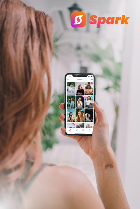 A person holding a phone that show a grid interface of a dating app