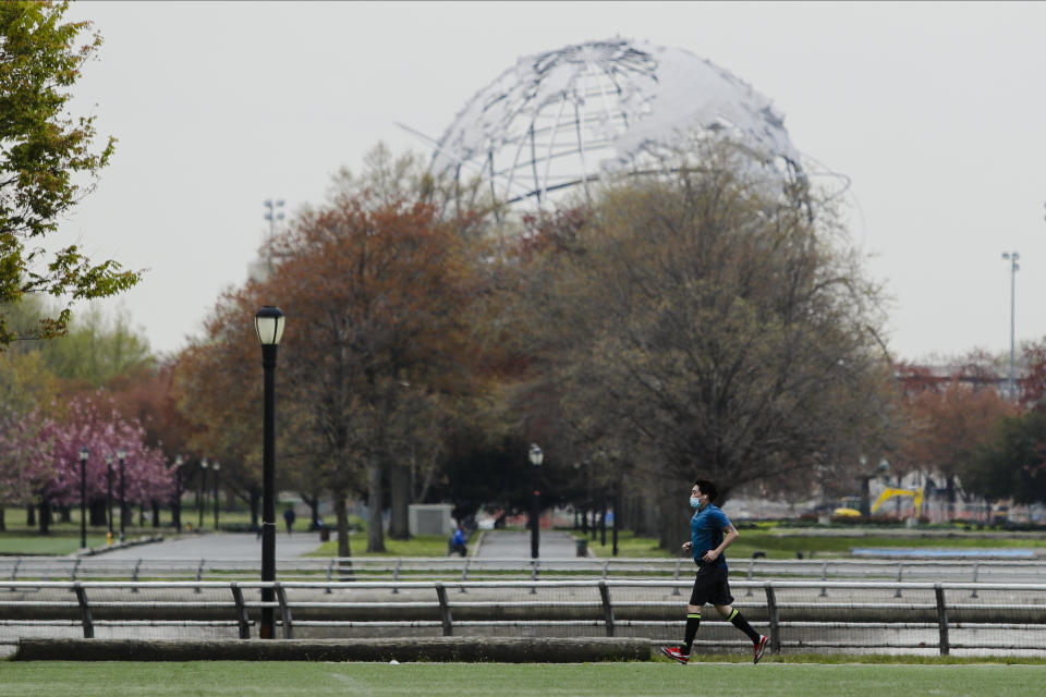 A man wearing a protective mask runs in Flushing Meadows-Corona Park Thursday, April 23, 2020, in the Queens borough of New York. (AP Photo/Frank Franklin II)