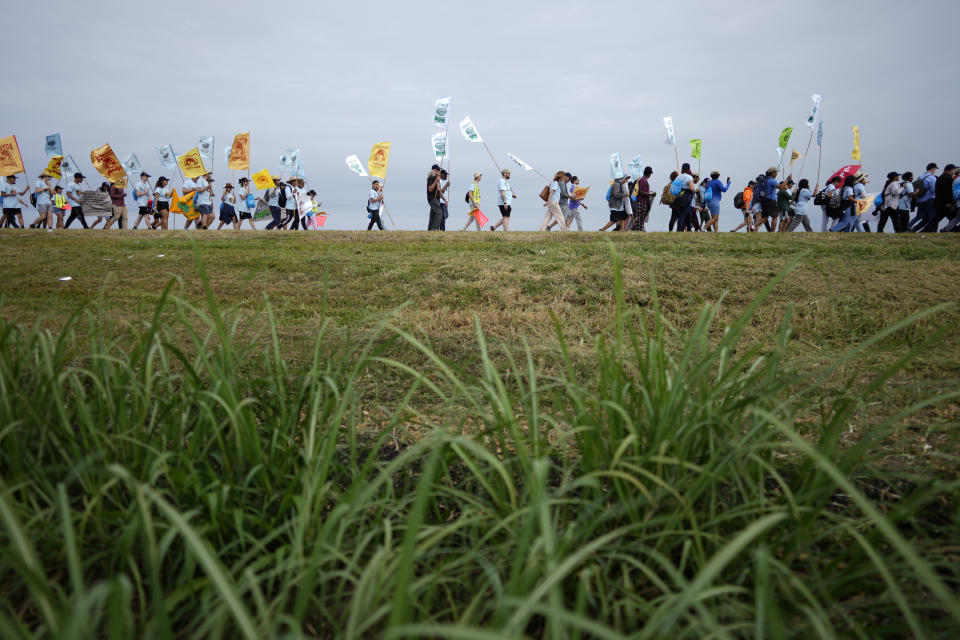 Farmworkers and allies march past fields at the start of a five-day trek aimed at highlighting the Fair Food Program, which has enlisted food retailers to use their clout with growers to ensure better working conditions and wages for farmworkers, Tuesday, March 14, 2023, in Pahokee, Fla. (AP Photo/Rebecca Blackwell)