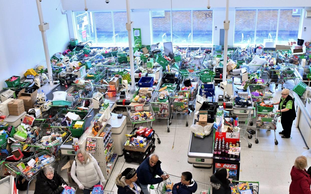  Trolleys piled high for delivery are seen as shoppers queue at the checkout of a supermarket in London March 2020 - JUSTIN TALLIS /AFP