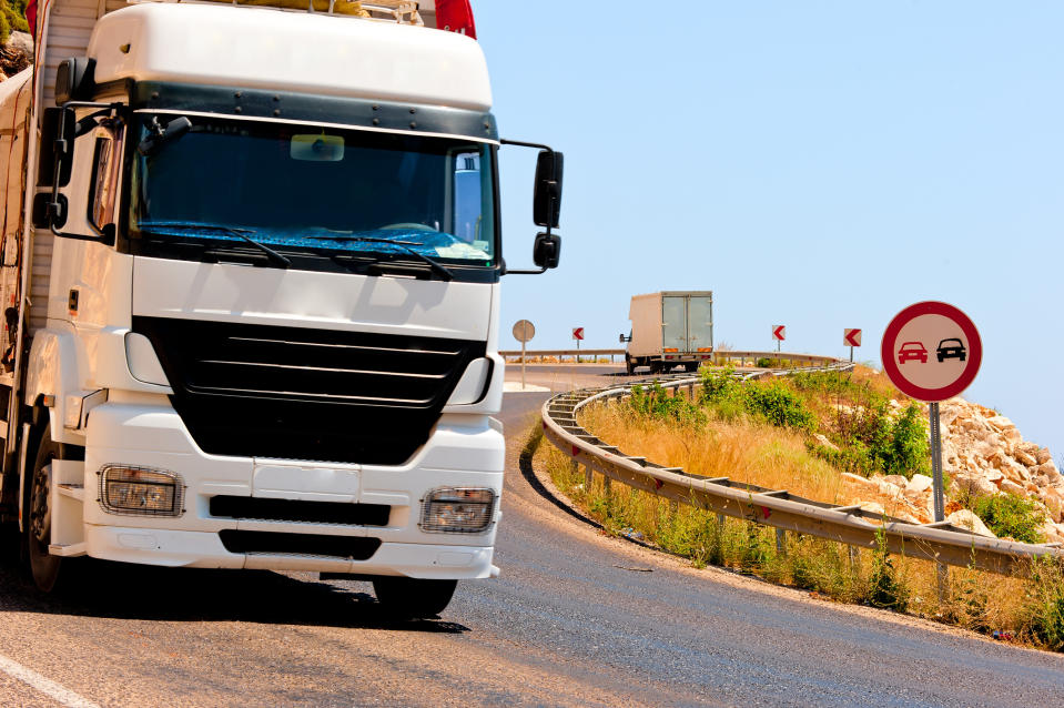 A truck driving downhill on a narrow mountain road.