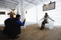 A couple takes a picture with a chair made of ice at the Ice Palace in Shangri-La Hotel in the northern city of Harbin, Heilongjiang province January 6, 2014. The Ice Palace, which is built by ice bricks, is open annually from December to February and attracts visitors during the Harbin Ice and Snow Festival. The temperatures inside the ice building is maintained around -10 degrees Celsius and it consists of bar and hot pot restaurant. REUTERS/Kim Kyung-Hoon (CHINA - Tags: SOCIETY TRAVEL ENVIRONMENT)