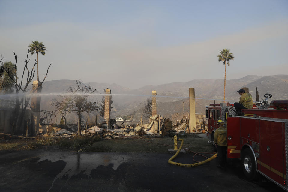 Bomberos arrojan agua el sábado 10 de noviembre de 2018 en lugares que siguen calientes tras el paso de un incendio en Malibú, California. (AP Foto/Marcio José Sánchez)