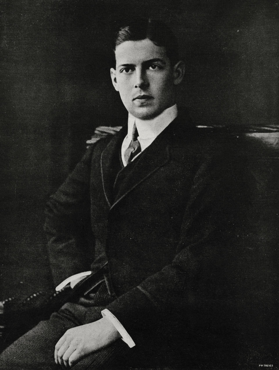 A historical black-and-white portrait of a man in a formal suit, seated and posing for the photograph