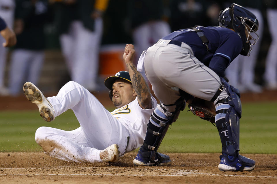 Oakland Athletics' Jace Peterson, left, scores next to Tampa Bay Rays catcher Francisco Mejia on a double by Brent Rooker during the seventh inning of a baseball game in Oakland, Calif., Tuesday, June 13, 2023. (AP Photo/Jed Jacobsohn)