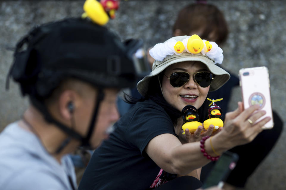 A protester takes a selfie with yellow ducks, which have become good-humored symbols of resistance during anti-government rallies, on Wednesday, Nov. 25, 2020, in Bangkok, Thailand. Thai authorities have escalated their legal battle against the students leading pro-democracy protests, charging 12 of them with violating a harsh law against defaming the monarchy. (AP Photo/Wason Wanichakorn)