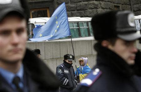 A protester holds a EU flag as police stand guard during a rally to support EU integration in front of the Ukrainian cabinet of ministers building in Kiev November 26, 2013. REUTERS/Vasily Fedosenko