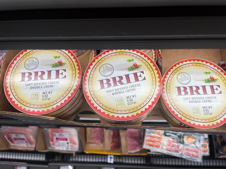Three containers of Brie cheese in a display at Aldi