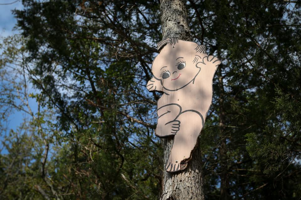 A painted Kewpie character pinned to a tree along Rose O'Neill Road, visible when driving to the Bonniebrook Art Gallery and Kewpie Museum, on Friday, Sept. 8, 2023.