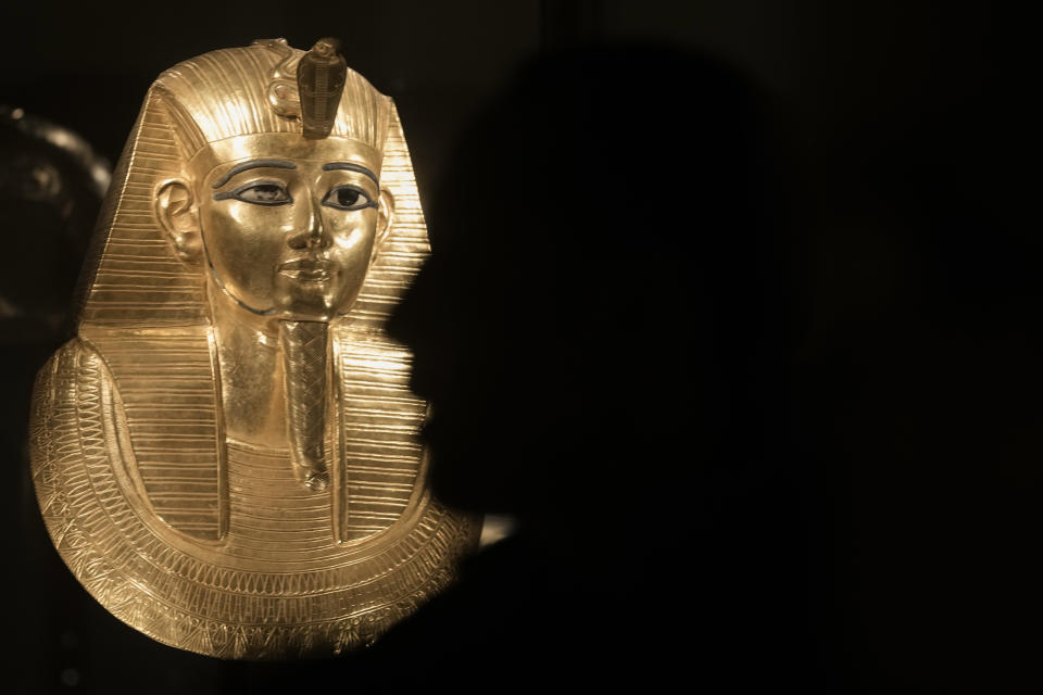 A visitor watches a recently displayed golden funerary mask of king Psusennes I, at the Egyptian museum in Cairo, Egypt, Monday, Feb. 20, 2023. Egypt's ministry of tourism and antiquities unveiled a renovated wing within its 120-year-old museum, the first stage of a broader replenishment program for the palatial building. (AP Photo/Amr Nabil)