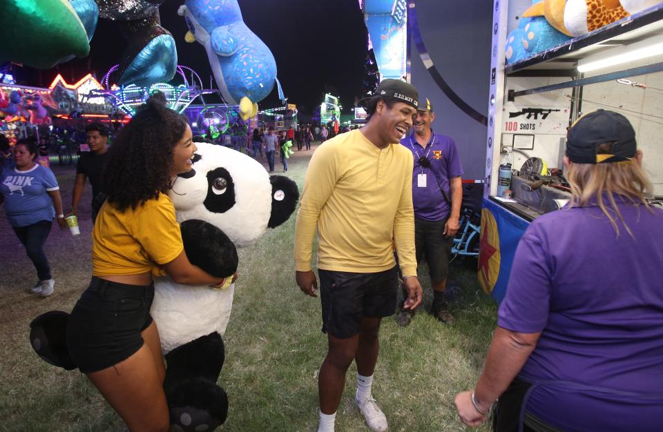 Veronica Schnuelle gets the prize that her boyfriend Chris Zavala won as he shot out a star to win a bear at the shooting booth at the Tulare County Fair in Tulare, Calif., Thursday, Sept. 15, 2022.