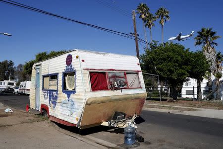 A plane flies over a homeless motorhome and tent encampment near LAX airport in Los Angeles, California, United States, October 26, 2015. REUTERS/Lucy Nicholson