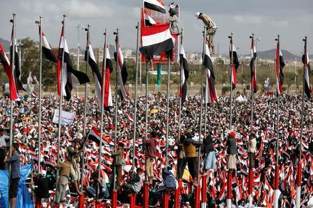 Supporters of the Houthi movement and Yemen's former president Ali Abdullah Saleh climb flag poles as they attend a joint rally to mark two years of the military intervention by the Saudi-led coalition, in Sanaa, Yemen March 26, 2017. REUTERS/Khaled Abdullah