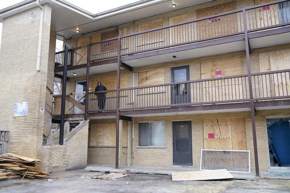 Guinevere Tyler watches from outside the second floor apartment she is living in and near where the stairs had collapsed, as Harvey, Ill., Mayor Christopher J. Clark tours the complex Monday, Jan. 8, 2024, in Harvey. Tyler, who was recently laid off from her meat factory job, heard noises outside and ran for a second door in her apartment thinking it was a break-in. She then came upon crews boarding up her windows. "I feel sick," she said, adding that she was too scared to return home. "I'm still sad." (AP Photo/Charles Rex Arbogast)