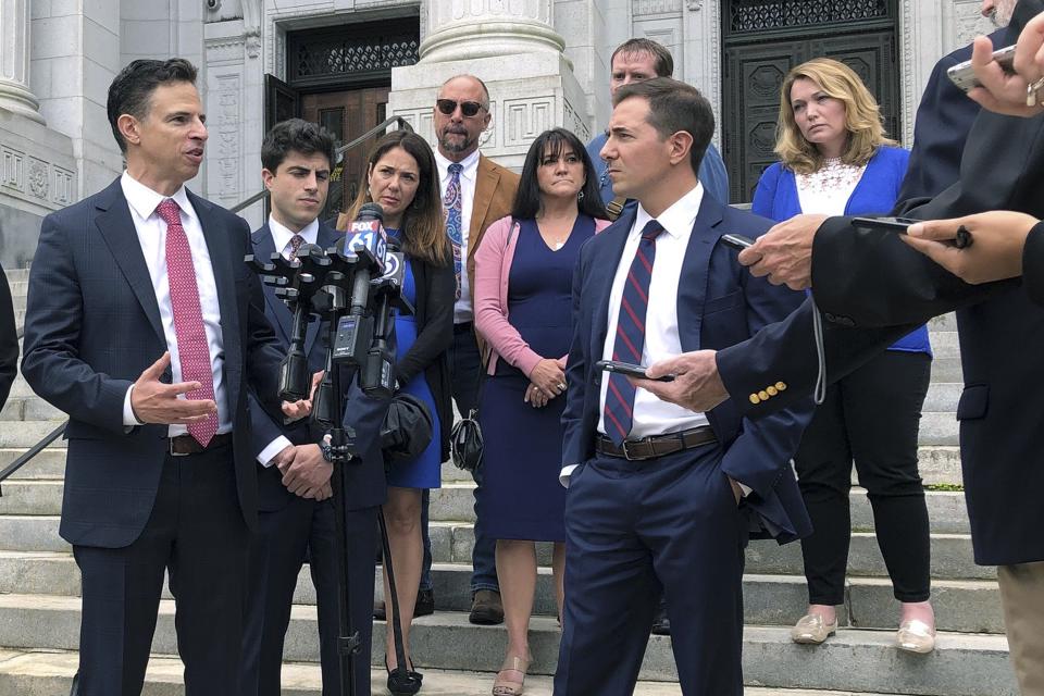 Attorneys Joshua Koskoff, left, and Christopher Mattei, right, representing parents, rear, of children killed in the 2012 Sandy Hook Elementary School shooting, speak outside the Connecticut Supreme Court, Thursday, Sept. 26, 2019, in Hartford, Conn. The lawyers argued that conspiracy theorist Alex Jones should be penalized for an outburst he made his Internet show against a lawyer for relatives of school shooting victims. (AP Photo/Dave Collins)