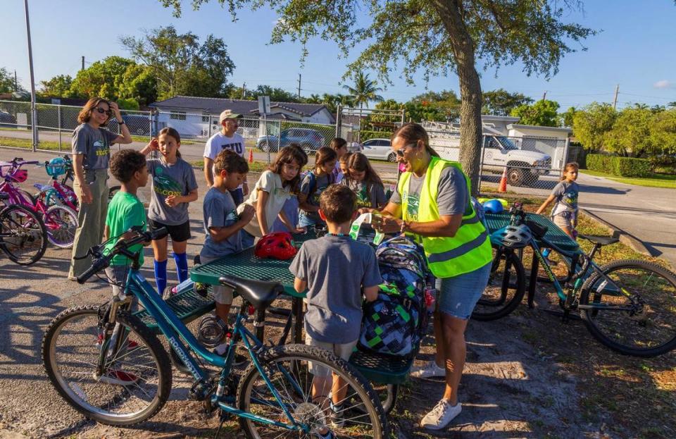 Mom Monique Gonzalez hands out stickers to a group of students who are part of The Springview Bike Bus after they rode their bikes to Springview Elementary School in Miami Springs, on Friday, May 24, 2024.
