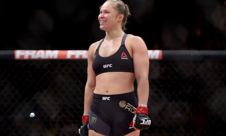 Ronda Rousey in the octagon with a huge smile on her face.