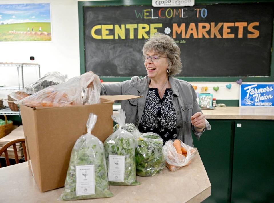 Sabine Carey looks through a box of product at Centre Markets new location in the Nittany Mall on Friday, March 22, 2024.