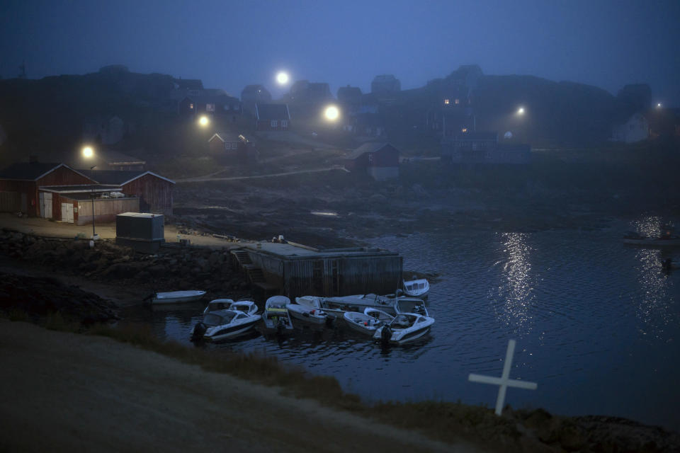 A cross sits on the side of the road as fog covers homes in Kulusuk, Greenland, early Thursday, Aug. 15, 2019. Greenland has been melting faster in the last decade and this summer, it has seen two of the biggest melts on record since 2012. (AP Photo/Felipe Dana)