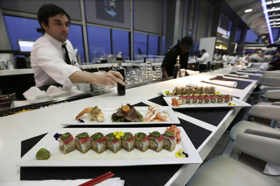 In this photo taken Tuesday, Dec. 18, 2012, at O'Hare International Airport in Chicago, a waiter delivers plates of fresh sushi at Wicker Park Seafood & Sushi in Terminal 2. Getting stranded at an airport once meant camping on the floor and enduring hours of boredom in a kind of travel purgatory with nothing to eat but fast food. Tough economic times are helping drive airports to make amends and transform terminals with a bit of bliss: spas, yoga studios, luxury shopping and restaurant menus crafted by celebrity chefs. (AP Photo/M. Spencer Green)