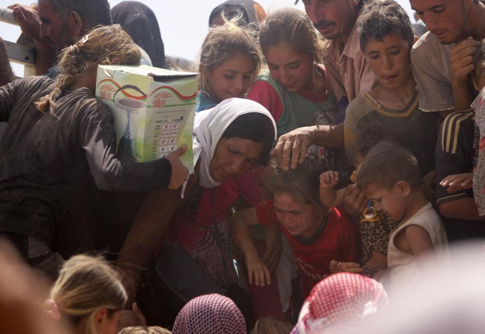 Displaced people from the minority Yazidi sect, fleeing violence from forces loyal to the Islamic State in Sinjar town, ride on a truck as they make their way towards the Syrian border